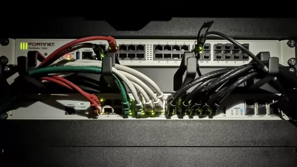 Netwerkrack met FortiGate-firewall en switches, aangesloten met gestructureerde netwerkbekabeling.