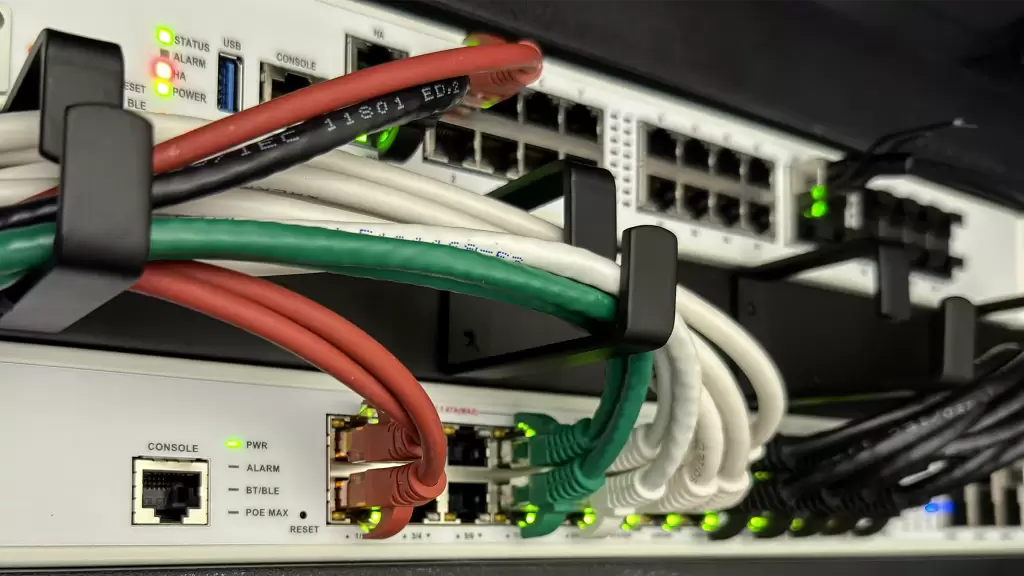 Gestructureerde netwerkbekabeling in kleur, aangesloten op een FortiGate-firewall en switch in een netwerkrack.