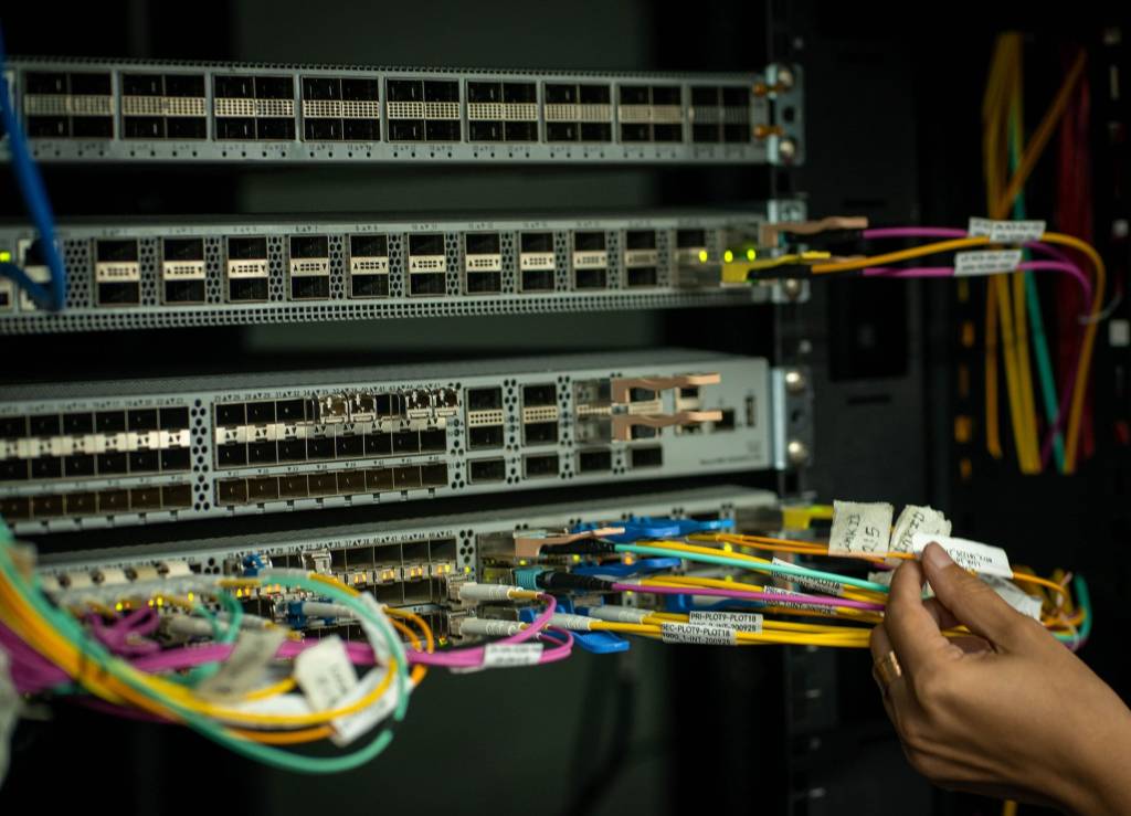 Glasvezel- en netwerkkabels aangesloten op switches in een serverrack.