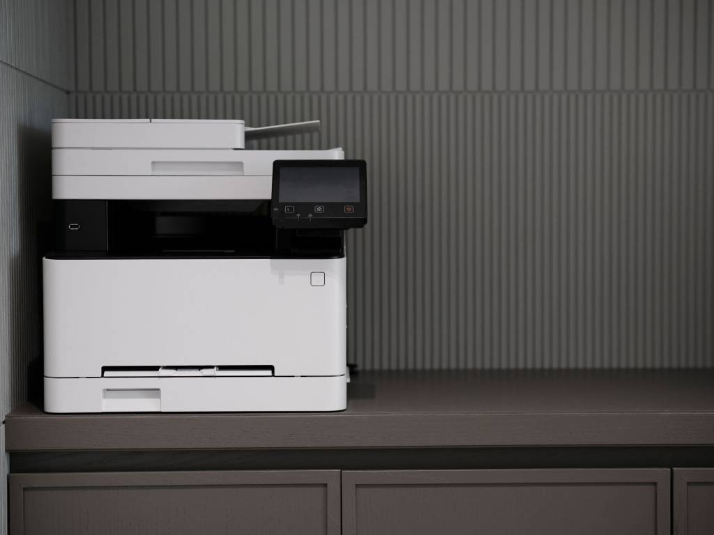 Moderne kantoorprinter op een kast tegen een rustige wand.