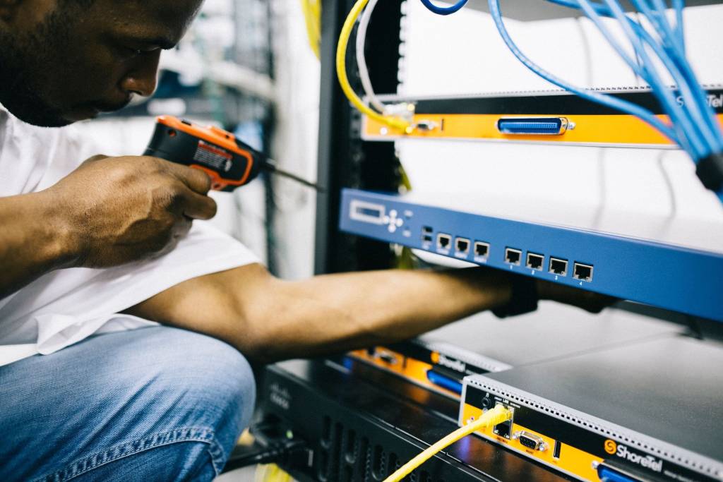 Technicus werkt met gereedschap aan netwerkapparatuur in een rack.