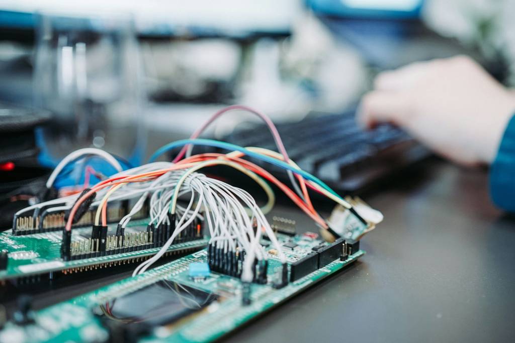 Printplaat met gekleurde kabels op een werkplek voor technische ontwikkeling.