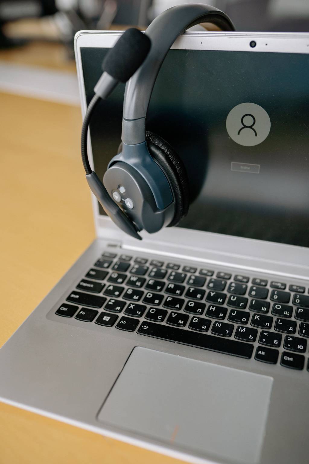 Headset hangt over het scherm van een laptop met aanmeldscherm.
