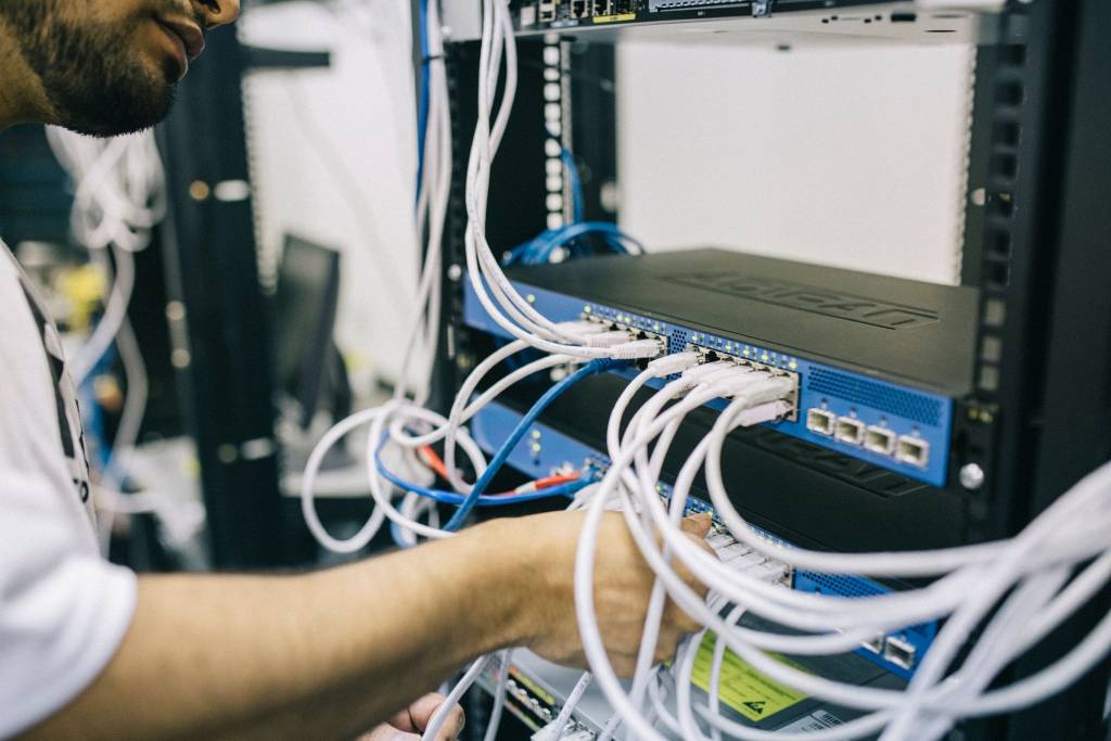Technicus sluit netwerkkabels aan op apparatuur in een serverrack.